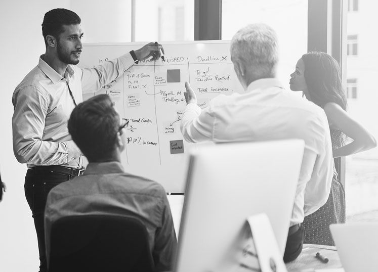 process flow employees studying material on whiteboard